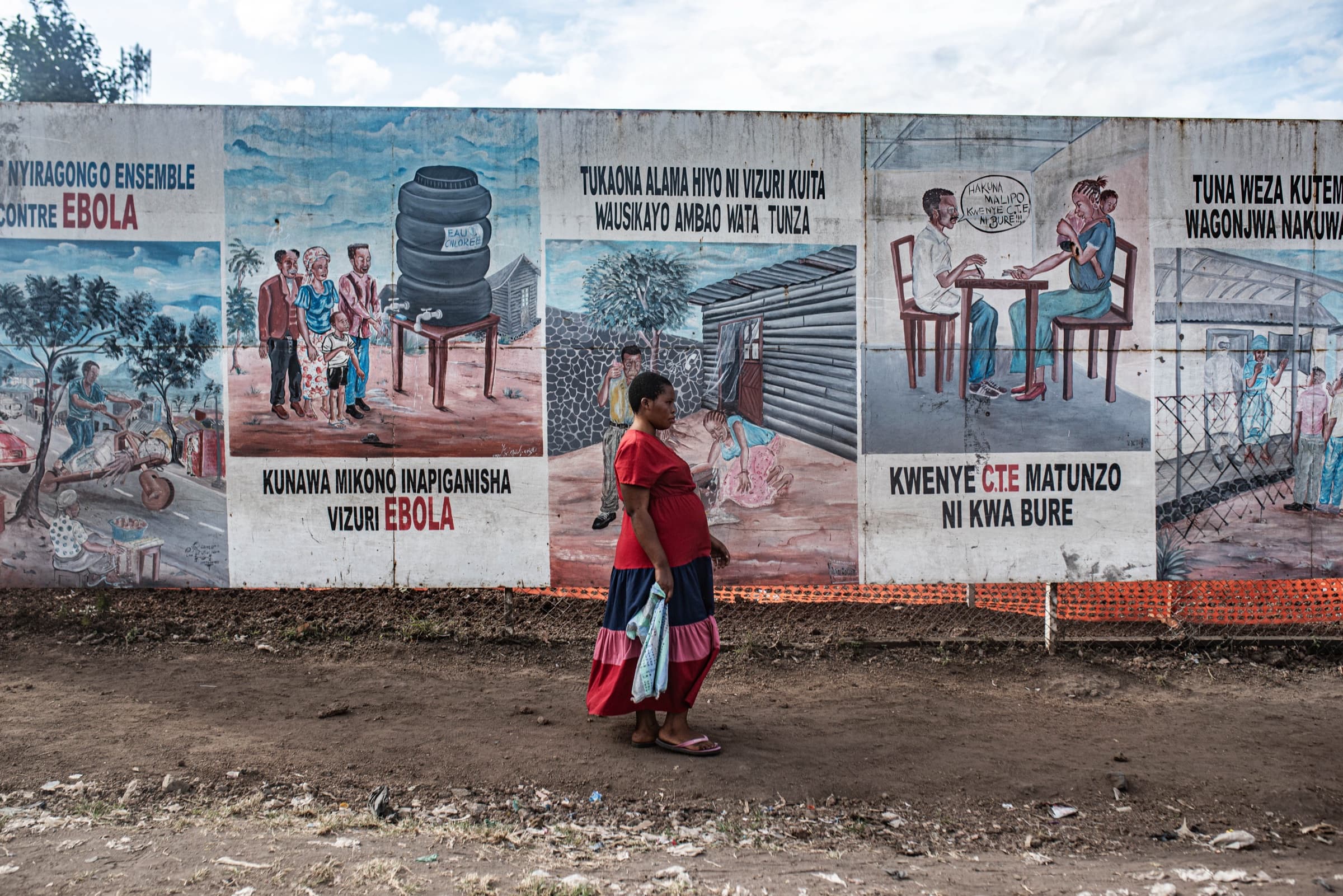A woman walks past a mural of Ebola prevention messages
